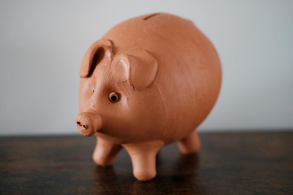 Close-up of a terracotta piggy bank on a wooden table, symbolizing savings.